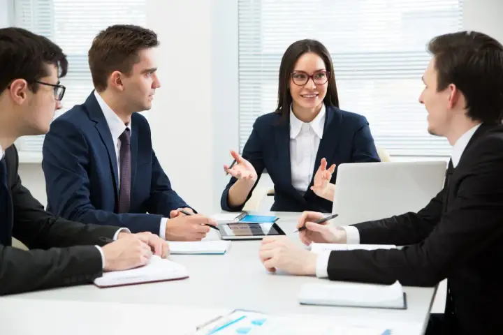 Team discute strategie di gestione del personale, analizzando dati su tablet e quaderni per ottimizzare le risorse umane.