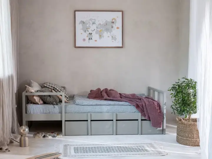 Przytulne łóżko dla nastolatków z szufladami, ozdobione mapą świata na ścianie. Idealne miejsce na marzenia o podróżach.