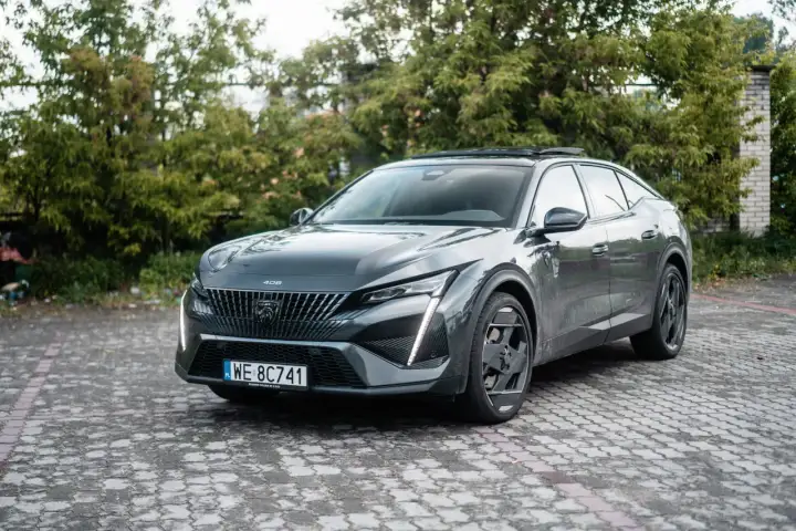 Szary Peugeot 408 na brukowanym podjeździe. Wiele osób szuka peugeot 408 opinie, ten model robi wrażenie.