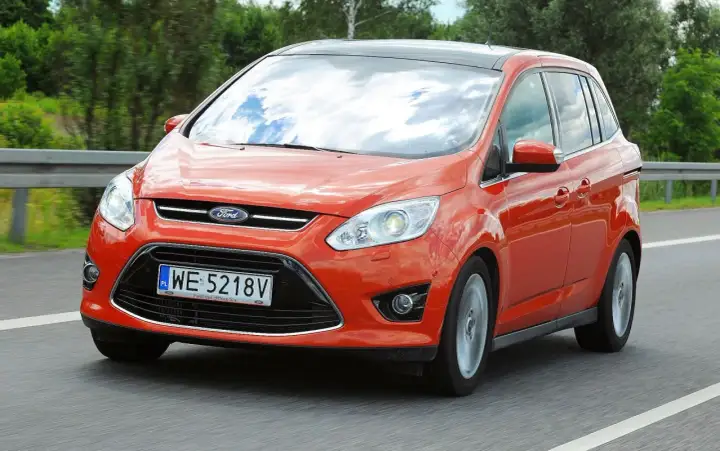 Pomarańczowy Ford C-Max na drodze. Wiele osób szuka ford c max opinie przed zakupem.