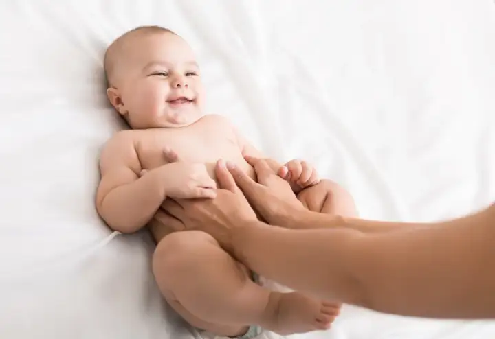 Glad bebis får magmassage på en vit bakgrund.