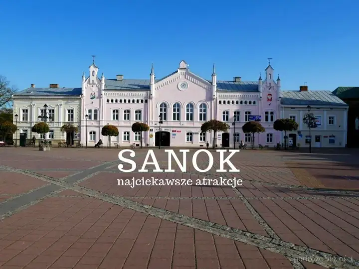 Różowy budynek ratusza na rynku w Sanoku, z napisem "Sanok najciekawsze atrakcje".