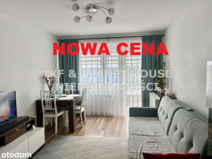 Nowa cena nieruchomości! Salon z jadalnią, kanapą i stołem. Okna z zasłonami.