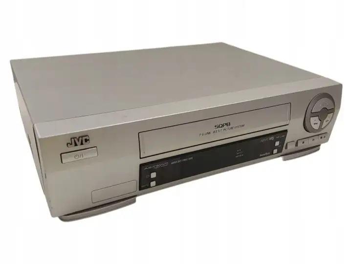 Srebrny vcr JVC z napisem SQPB. Urządzenie posiada przyciski sterujące i slot na kasetę.