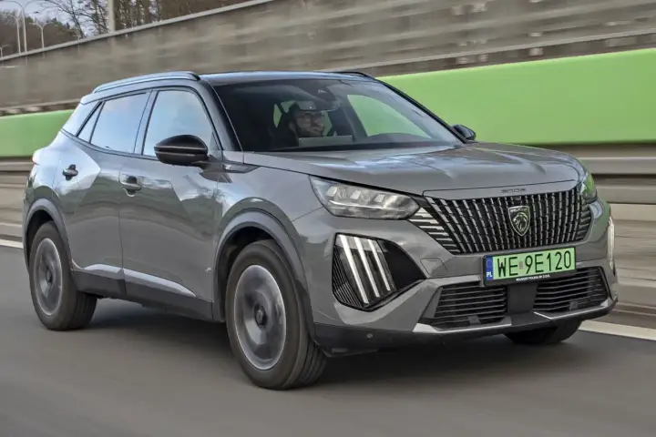 Szary Peugeot 2008 na drodze, kierowca w okularach. Sprawdź aktualną peugeot 2008 cena.