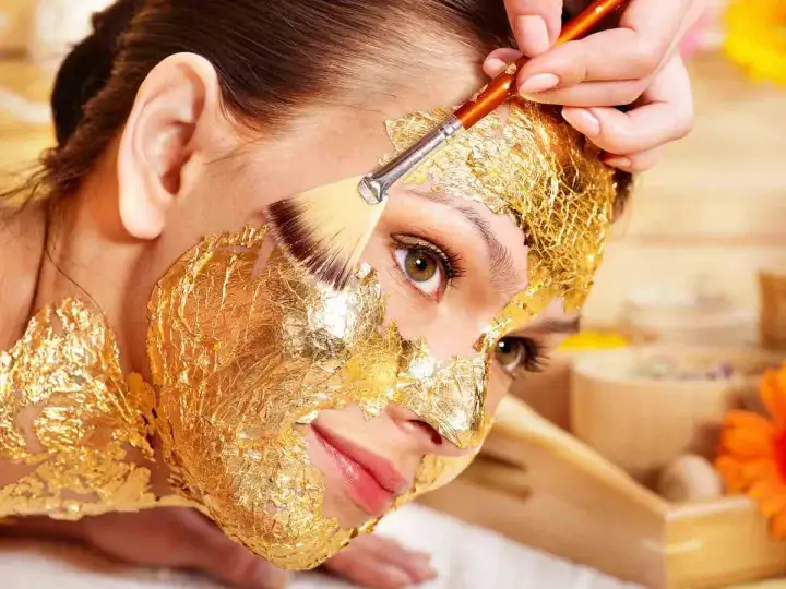 Una donna riceve un trattamento di bellezza con una maschera viso oro, scoprendo i suoi benefici rigeneranti.