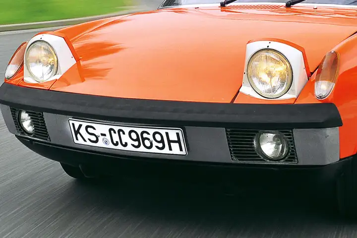 Vorderansicht eines orangefarbenen Oldtimers mit Klappscheinwerfern. Ab wann ist ein Oldtimer steuerfrei?