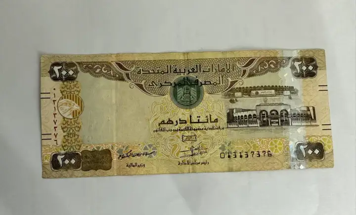 Banknot 200 dirhamów Zjednoczonych Emiratów Arabskich z wizerunkiem sokoła i budynków.