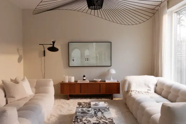 Vardagsrum inspiration beige med mjuka soffor, marmorbord och en konstnärlig taklampa.