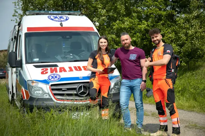 Trzech ratowników medycznych przy ambulansie. Zastanawiasz się, ile zarabia ratownik medyczny?