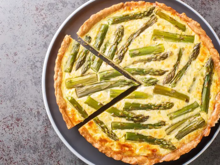 Eine köstliche Spargel Quiche mit einem goldbraunen Teigrand und saftiger Füllung, belegt mit frischem Spargel.