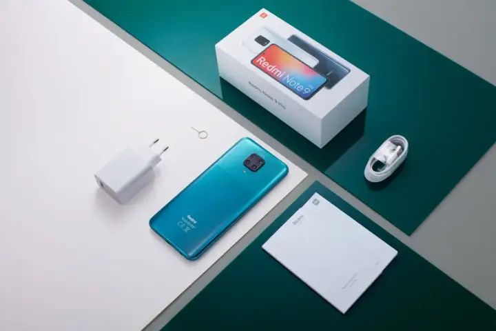 Zestaw Xiaomi Redmi Note 9 Pro: turkusowy telefon, ładowarka, kabel, instrukcja i pudełko. Aparat tego modelu robi świetne zdjęcia.