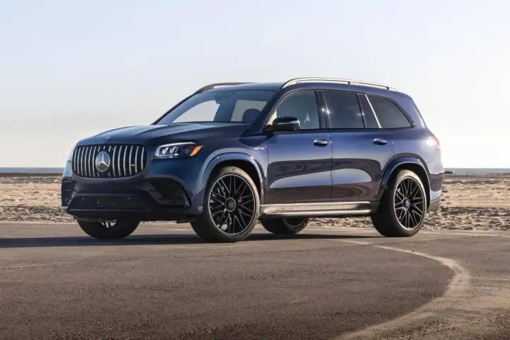Lśniący, granatowy Mercedes-Benz GLS z czarnymi felgami stoi na asfalcie przy plaży.