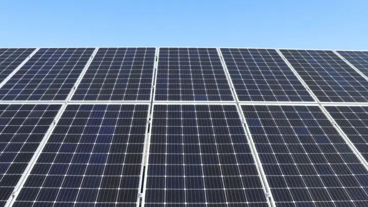 Duża instalacja PV pod błękitnym niebem. Panele słoneczne tworzą równą, ciemną powierzchnię, gotową do produkcji czystej energii.