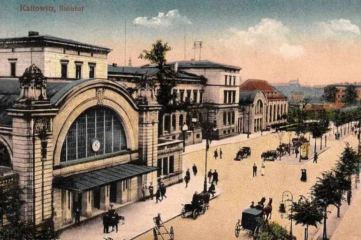 Dawny dworzec w Katowicach z epoki, z dorożkami i pieszymi na brukowanym placu.