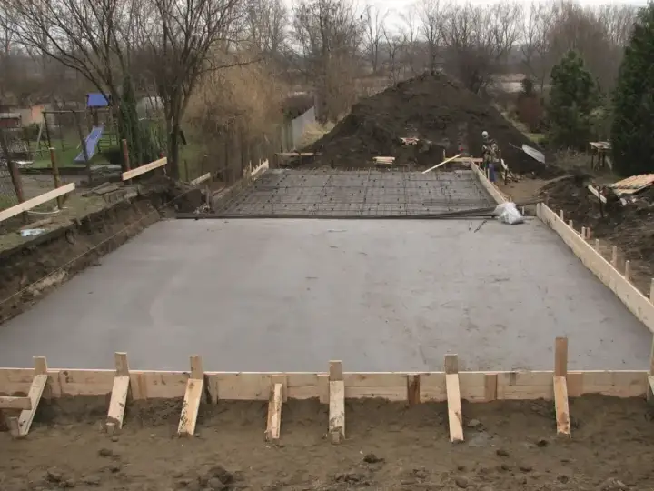Plac budowy z wylana betonowa płyta fundamentowa i zbrojenie.