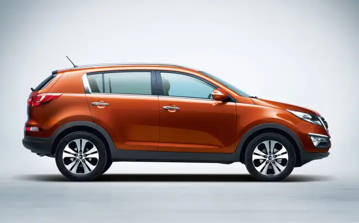 Pomarańczowy Kia Sportage 2013 z profilu, z błyszczącymi felgami i chromowanymi klamkami, gotowy na przygodę.
