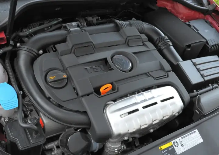 Silnik 1.4 TSI z widocznym logo VW. Widoczne elementy układu dolotowego i osłony silnika.