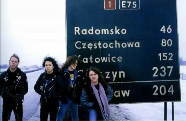 Czterech muzyków zespołu Metallica pozuje przy drogowskazie w Polsce. Może to zapowiedź ich koncertu Metallica Polska 2026?