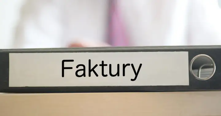 Segregator z napisem "Faktury" na biurku, gotowy do uporządkowania dokumentacji.