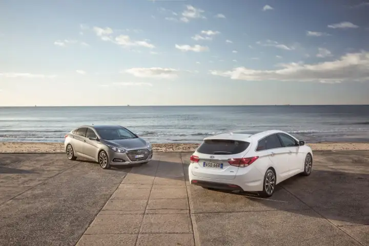 Dwa Hyundai i40, sedan i kombi, stoją nad brzegiem morza. Wiele pozytywnych hyundai i40 opinie potwierdza ich wszechstronność.