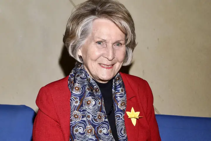 Uśmiechnięta Irena Santor w czerwonej marynarce i wzorzystym szalu. Wiele osób zastanawia się, ile lat ma Irena Santor, a jej wygląd świadczy o witalności.