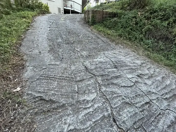 Stromy podjazd z popękanego betonu, z widocznymi śladami po koleinach. Zastanawiasz się, czym wyłożyć stromy podjazd?