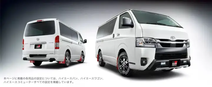 Dwa białe vany Toyota Hiace z pakietem GR Parts. Jeden z tyłu, drugi z przodu, oba z czerwonymi chlapacami.
