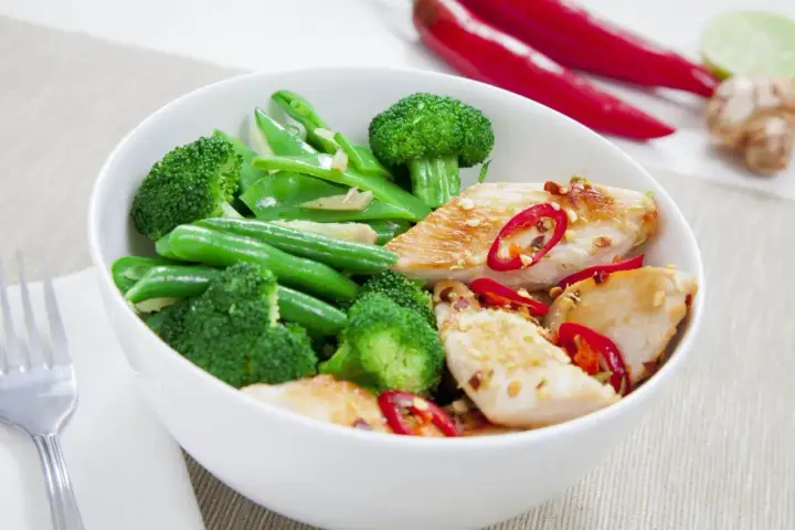 Miseczka z kurczakiem, brokułami i fasolką szparagową, posypana chili. Idealne danie na dieta białkowo tłuszczowa.