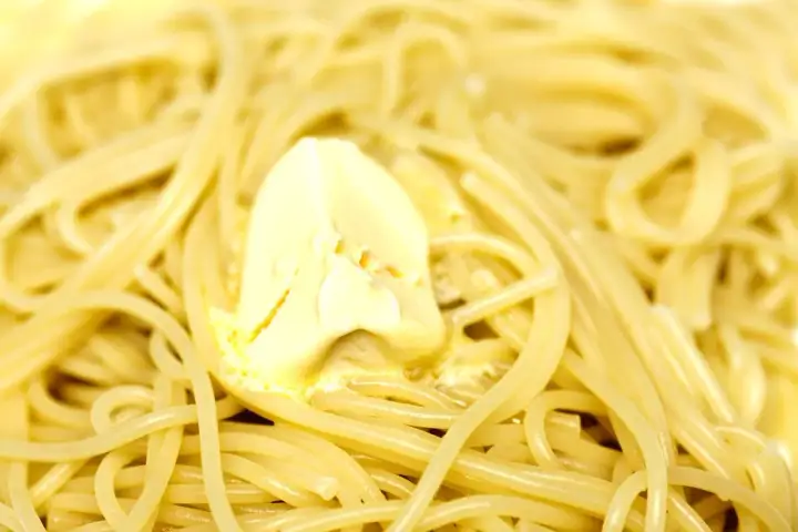 Spaghetti fumanti con una generosa porzione di burro che si scioglie, un classico piatto di pasta in bianco.