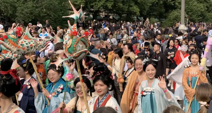 Bunte Drachenköpfe und Menschen in traditionellen Gewändern beleben den **Carnival Berlin**. Eine fröhliche Parade zieht durch die Menge.