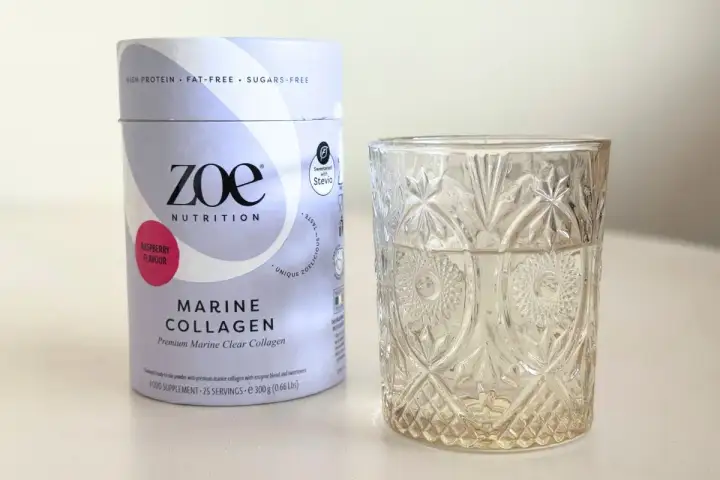 Opakowanie Zoe Nutrition Marine Collagen o smaku malinowym obok szklanki. Czy warto kupić? Sprawdź collagen drink dr max opinie.