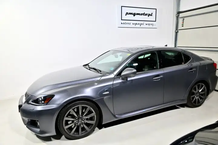 Szary Lexus IS F w garażu, z logo "pmgmotopl" na ścianie.