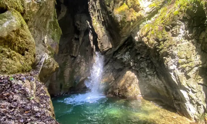 Piccola cascata in una gola rocciosa, con acqua cristallina che forma una pozza. Un luogo incantevole vicino al Lago di Garda.