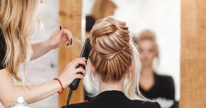 Fryzjerka stylizuje eleganckie upięcie. Zastanawiasz się, ile zarabia fryzjer? To zależy od wielu czynników, ale umiejętności i doświadczenie są kluczowe.