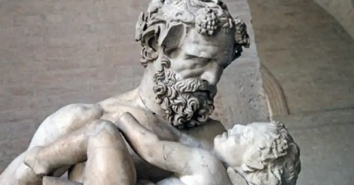 Sculpture d'un homme barbu portant un enfant, évoquant la **mythologie** de **Zagreus**. L'homme, couronné de pampres, serre tendrement le petit corps.