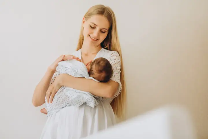Szczęśliwa mama z niemowlęciem na rękach. To piękny okres karmienia piersią, pełen bliskości i miłości.