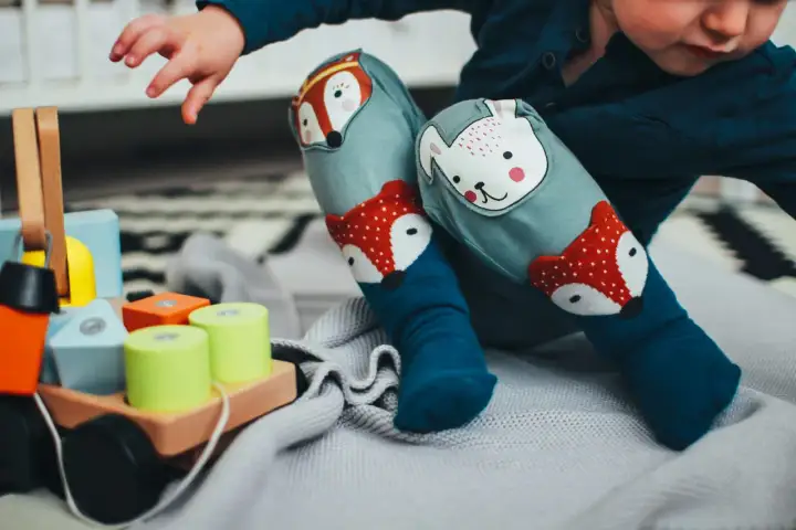 Dziecko w kolorowych skarpetkach z liskiem i misiem bawi się klockami. Wesołe zabawy dla dzieci w żłobku.