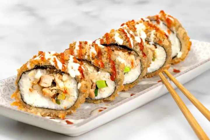 Knusprig frittiertes Sushi mit Hühnchen und Gemüse, beträufelt mit Saucen. Ein köstlicher Genuss!