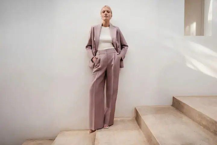 Elegancki różowy garnitur w prążki to idealna propozycja, jak się ubrać na poprawiny. Luźne spodnie i marynarka tworzą stylowy look.