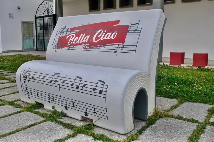 Ławka w kształcie książki z nutami i napisem "Bella Ciao tekst".