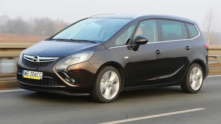 Ciemnobrązowy Opel Zafira Tourer 1.4 Turbo na drodze. Kierowca za kierownicą.