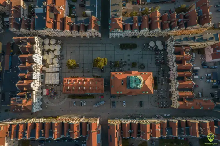 Widok z lotu ptaka na rynek w Jeleniej Górze. Widać kolorowe kamienice, kawiarniane ogródki i zabytkowy ratusz. To świetne miejsce na odkrywanie jeleniogórskich atrakcji.