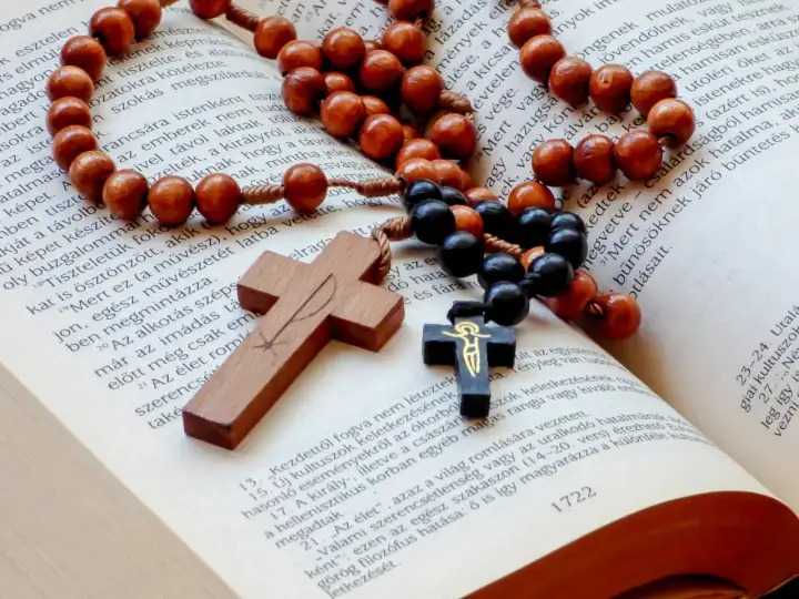 Drewnany różaniec i krzyż na otwartej Biblii. Symbolika modlitwy i wiary, która towarzyszy, kiedy zaczyna działać nowenna pompejańska.