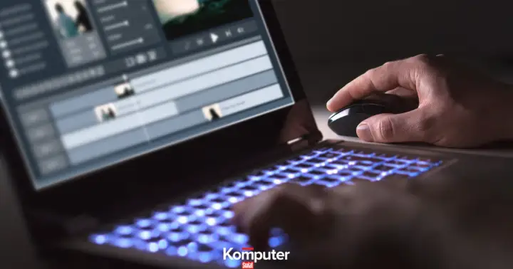 Dłoń steruje myszką przy laptopie z podświetlaną klawiaturą, edytując wideo w formacie HEVC.