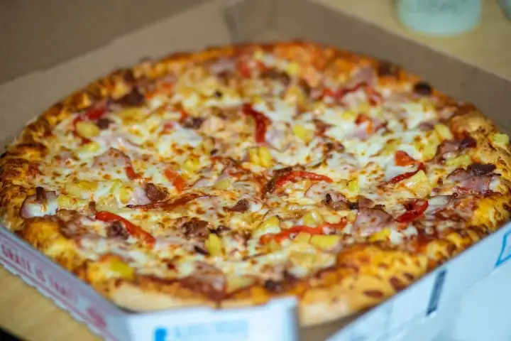 Pyszna pizza hawajska w pudełku, idealna do szybkiego odgrzania w mikrofali.