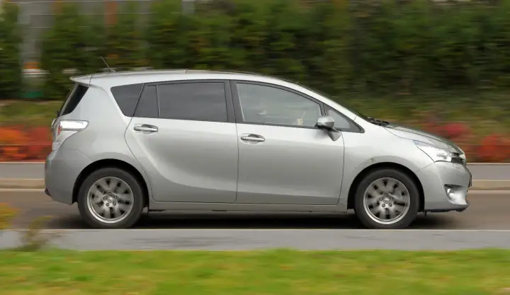 Srebrna Toyota Verso w ruchu. Zastanawiasz się nad jej wadami i zaletami? Ten rodzinny minivan oferuje przestronne wnętrze i komfort.