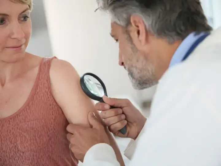 Dermatolog bada pieprzyk u pacjentki. Czy do dermatologa na NFZ potrzebne jest skierowanie? Sprawdź!