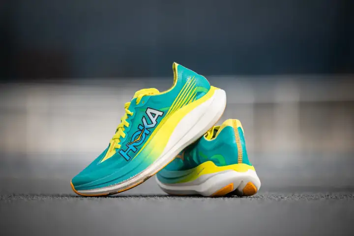 Paire de chaussures de course Hoka Rocket X 2, turquoise et jaune vif, prêtes pour un test de performance.