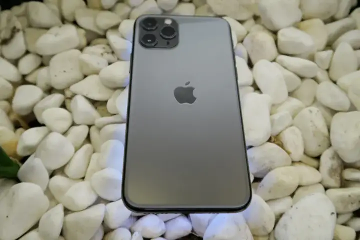 Szary iPhone 11 Pro leży na białych kamieniach. To urządzenie iPhone niedostępne, ale wciąż piękne.